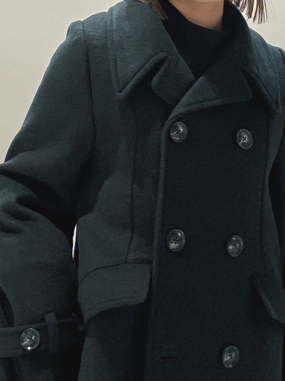 ホワイト系のハンドバッグ、ブラック系のワンピース、グリーン系のチェスターコートを着用したレディースの冬コーディネートの7枚目の写真