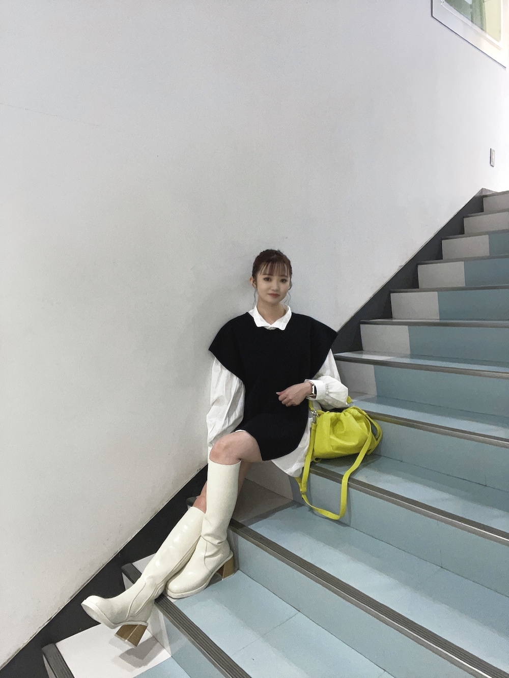 イエロー系のハンドバッグ、ブラック系のワンピースを着用したレディースの夏コーディネートの3枚目の写真