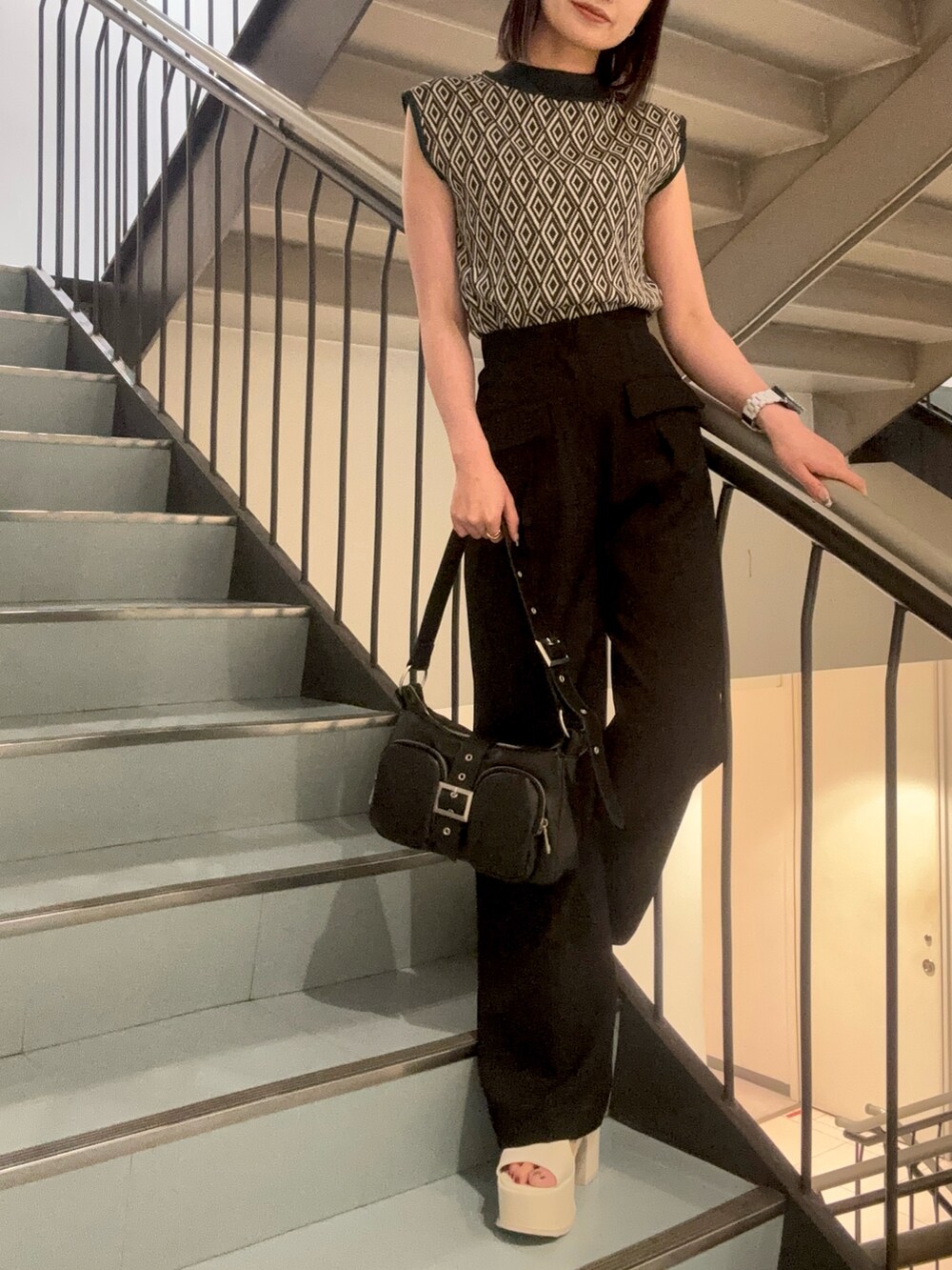 ホワイト系のサンダル、ブラック系のハンドバッグ、グリーン系のタンクトップを着用したレディースの夏コーディネートの6枚目の写真