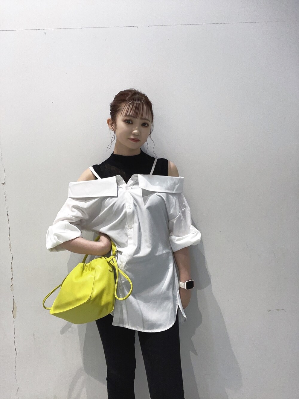 イエロー系のハンドバッグ、ホワイト系のシャツ/ブラウス、ブラック系のブーツを着用したレディースの夏コーディネートの2枚目の写真