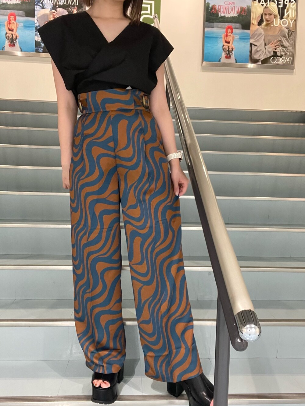 ブラック系のシャツ/ブラウス、ブルー系のスラックス、ホワイト系のハンドバッグを着用したレディースの夏コーディネートの5枚目の写真