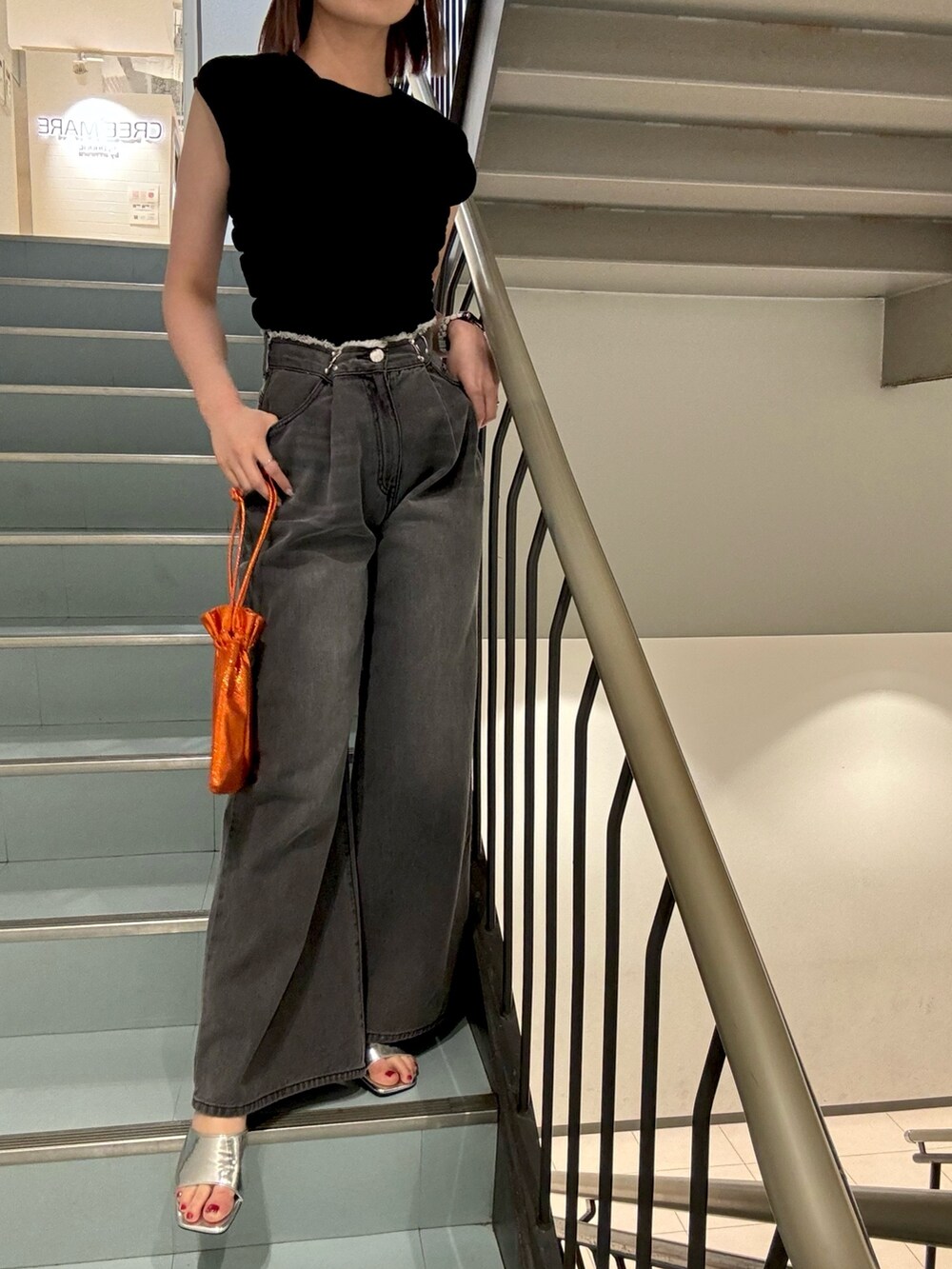 オレンジ系のショルダーバッグ、ブラック系のTシャツ/カットソー、ブラック系のデニムパンツを着用したレディースの夏コーディネートの6枚目の写真