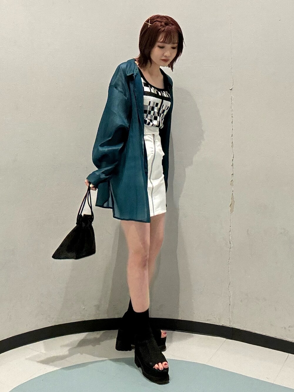 ブラック系のブーツ、ホワイト系のスカート、グリーン系のシャツ/ブラウスを着用したレディースの春コーディネートの2枚目の写真