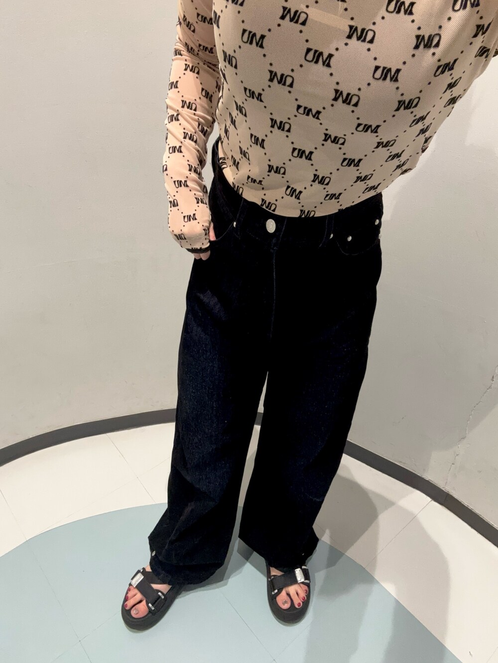 ブラック系のデニムパンツ、ベージュ系のTシャツ/カットソー、ブラック系のサンダルを着用したレディースの夏コーディネートの6枚目の写真