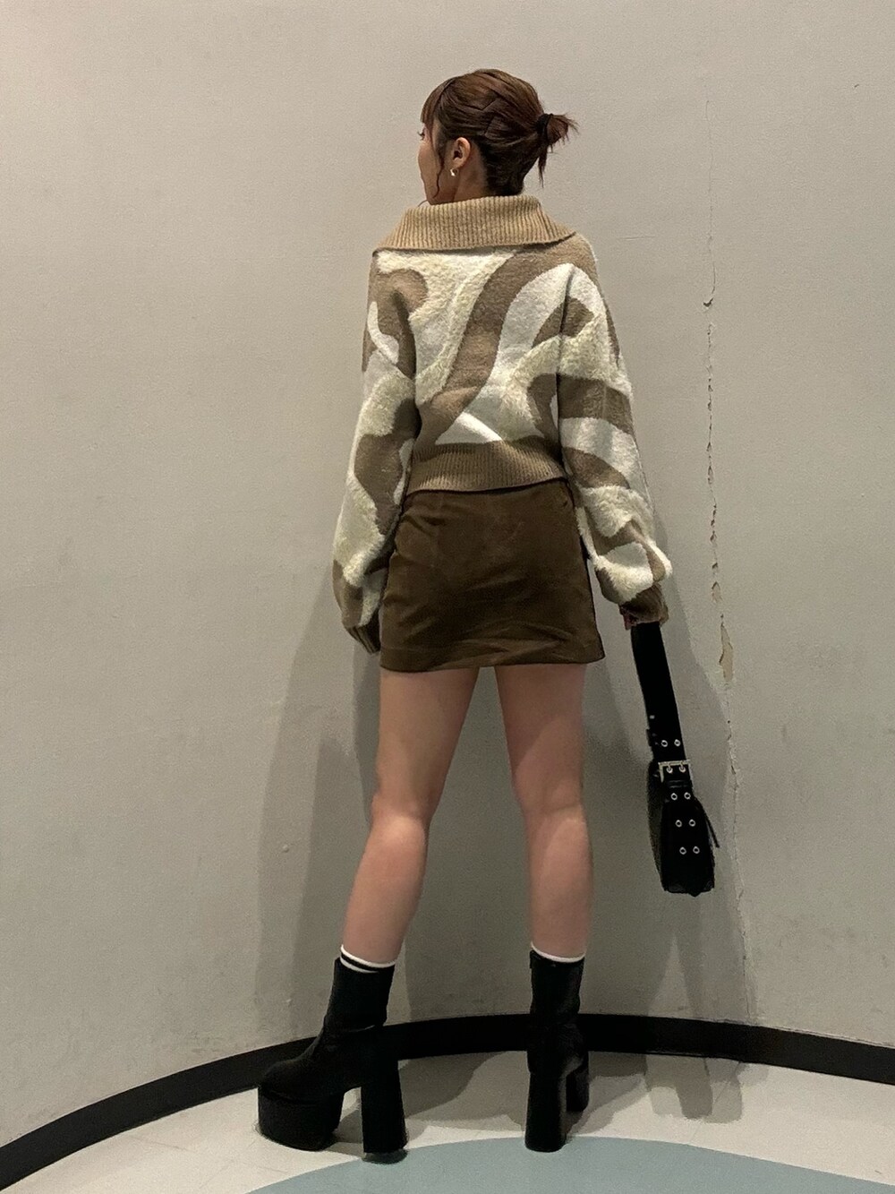 ホワイト系のニット/セーター、ブラウン系のスカート、ブラック系のブーツを着用したレディースの秋コーディネートの2枚目の写真