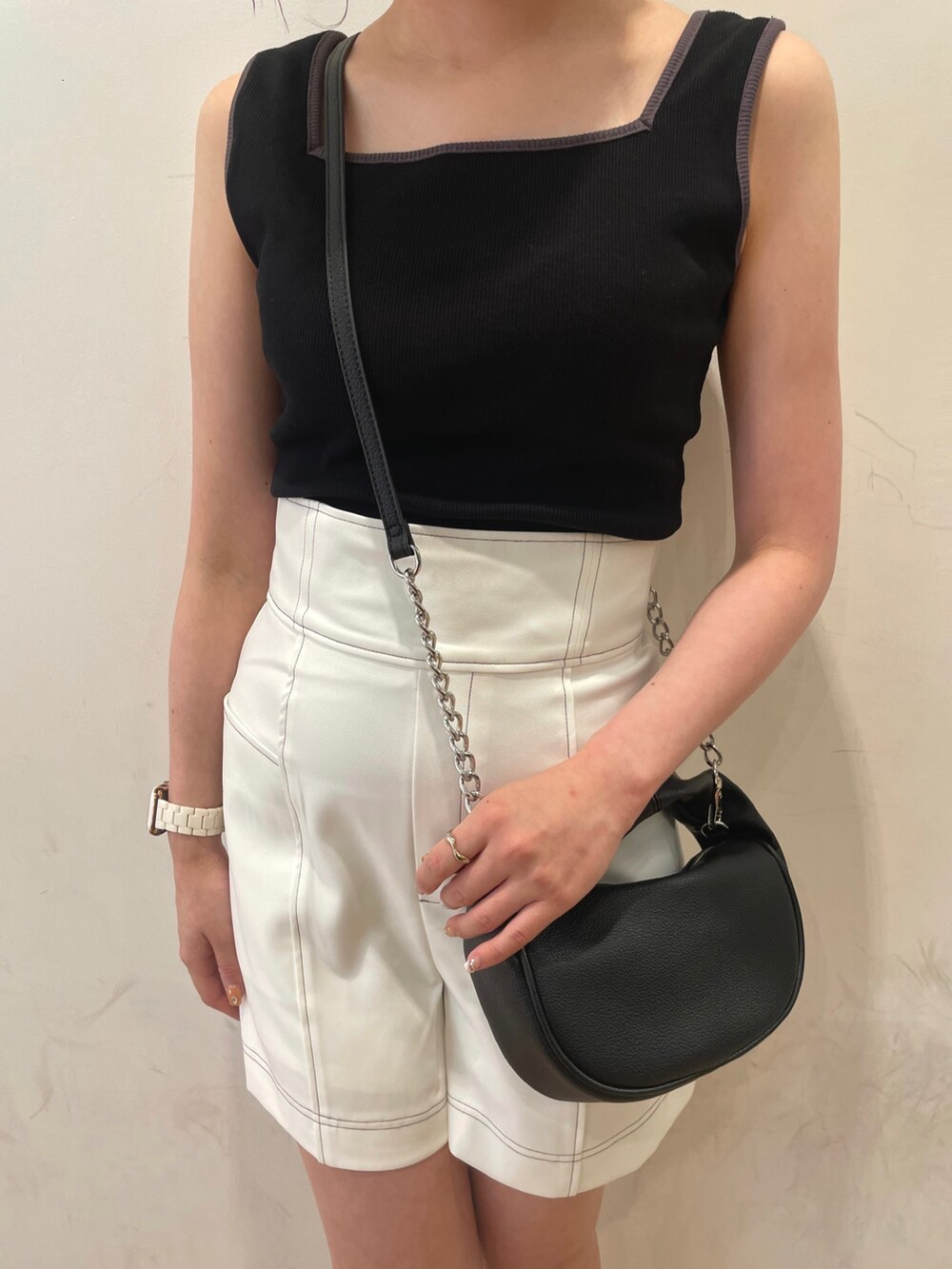 ブラック系のハンドバッグ、ブラック系のサンダル、オレンジ系のベストを着用したレディースの夏コーディネートの6枚目の写真