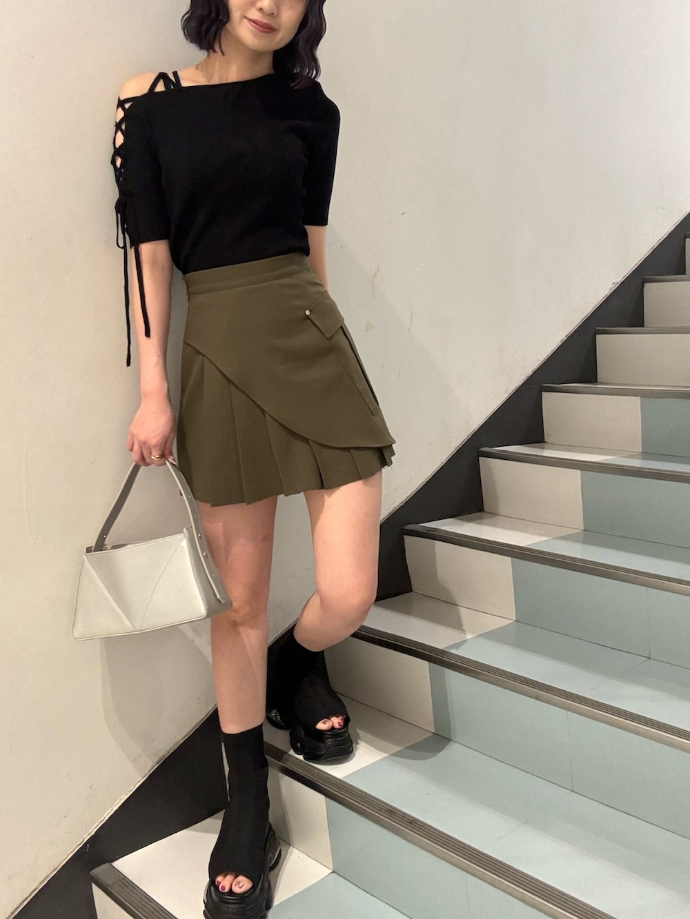 シルバー系のハンドバッグ、ブラック系のサンダル、ブラック系のニット/セーターを着用したレディースの夏コーディネートの5枚目の写真