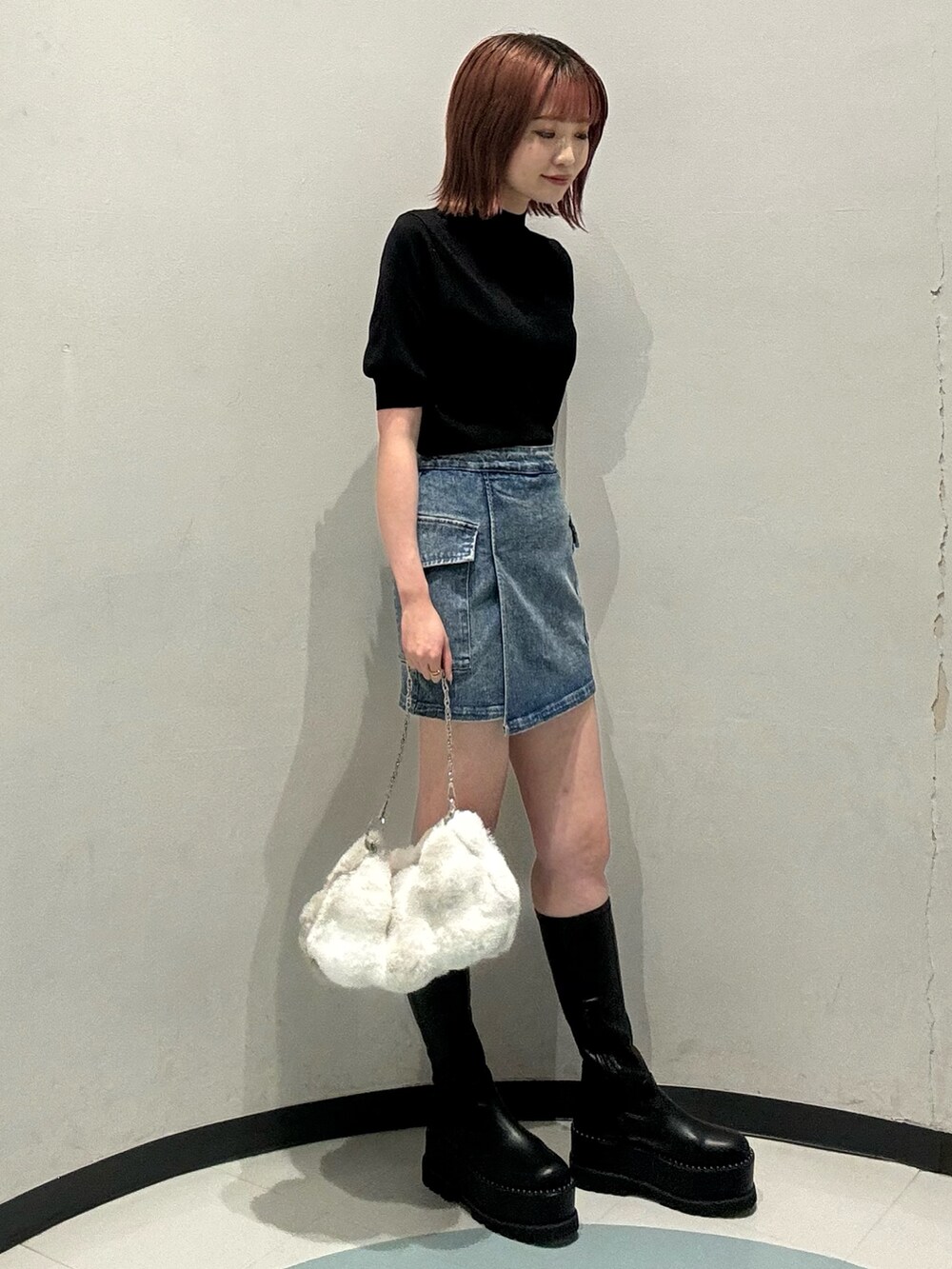 ブラック系のニット/セーター、ブルー系のスカート、ブラック系のブーツを着用したレディースの夏コーディネートの2枚目の写真