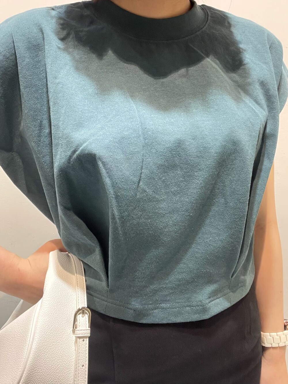 ホワイト系のハンドバッグ、ブラック系のサンダル、グリーン系のTシャツ/カットソーを着用したレディースの春コーディネートの4枚目の写真