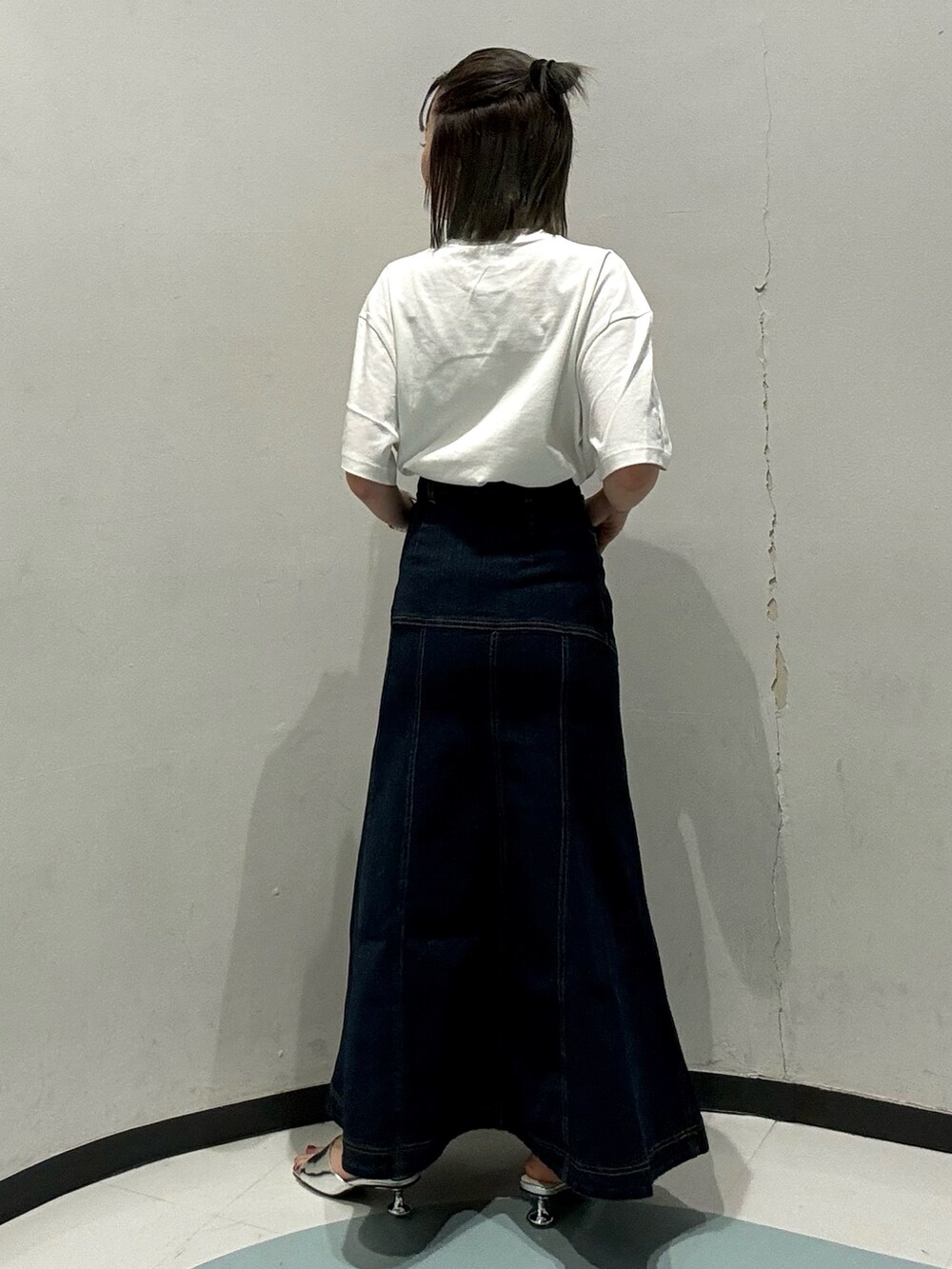 ブルー系のデニムスカート、ホワイト系のTシャツ/カットソー、シルバー系のサンダルを着用したレディースの春コーディネートの3枚目の写真