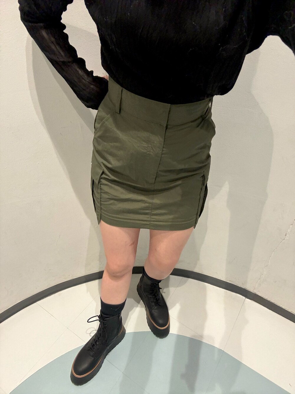 ブラック系のニット/セーター、ホワイト系のベスト、グリーン系のスカートを着用したレディースの秋コーディネートの7枚目の写真