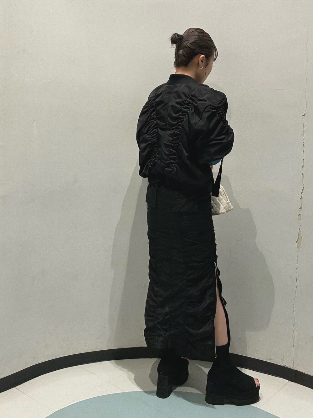 ブラック系のスカート、ホワイト系のハンドバッグ、ブラック系のブルゾンを着用したレディースの春コーディネートの4枚目の写真