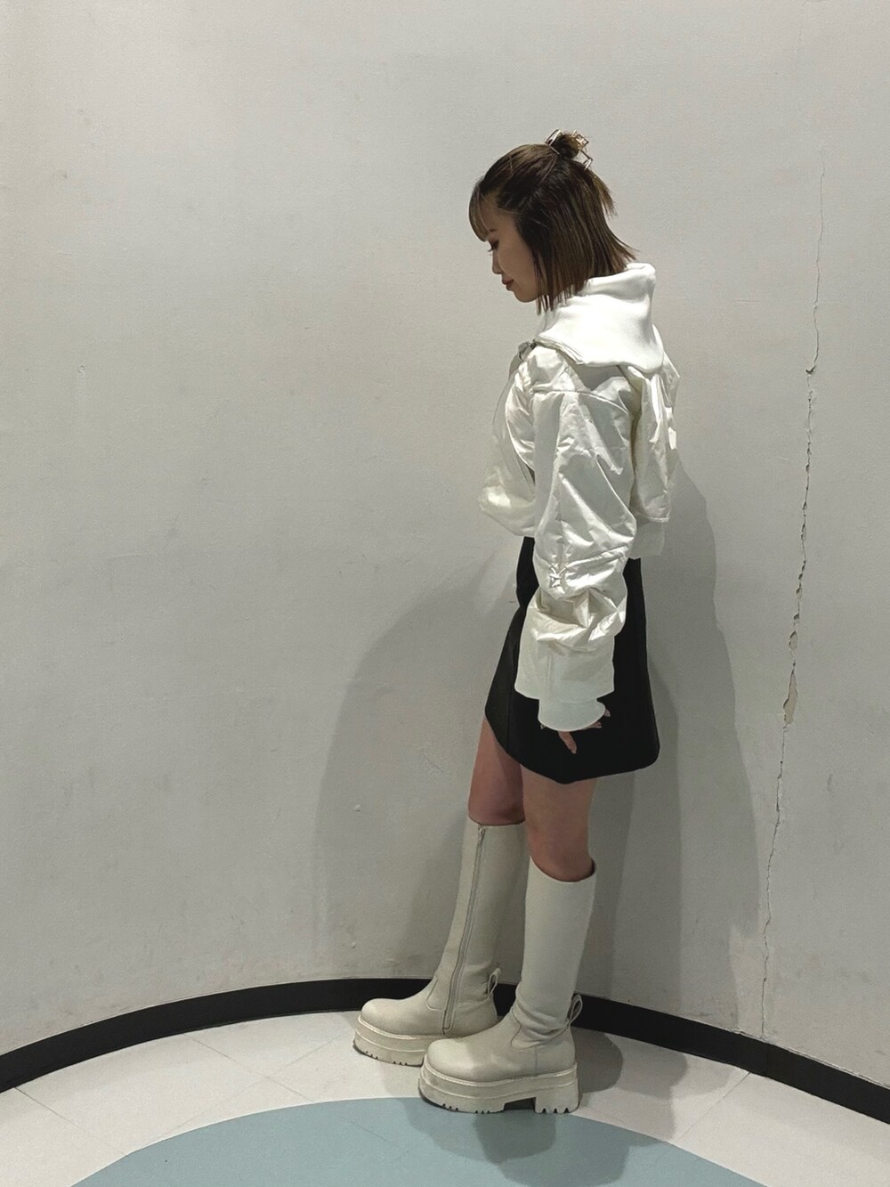 ブルー系のニット/セーター、ホワイト系のブルゾン、ブラック系のスカートを着用したレディースの冬コーディネートの4枚目の写真