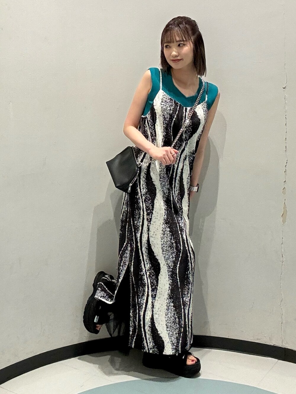 ブラック系のワンピース、ブラック系のハンドバッグ、グリーン系のニット/セーターを着用したレディースの春コーディネートの2枚目の写真