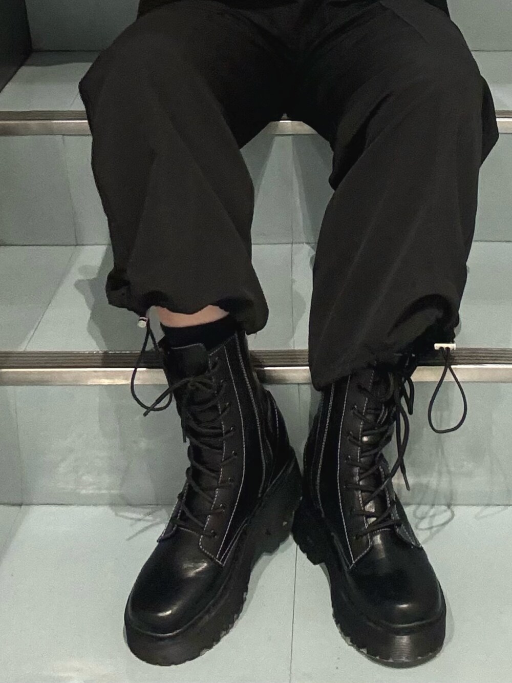 ブルー系のニット/セーター、ブラック系のその他パンツ、ブラック系のブーツを着用したレディースの冬コーディネートの6枚目の写真