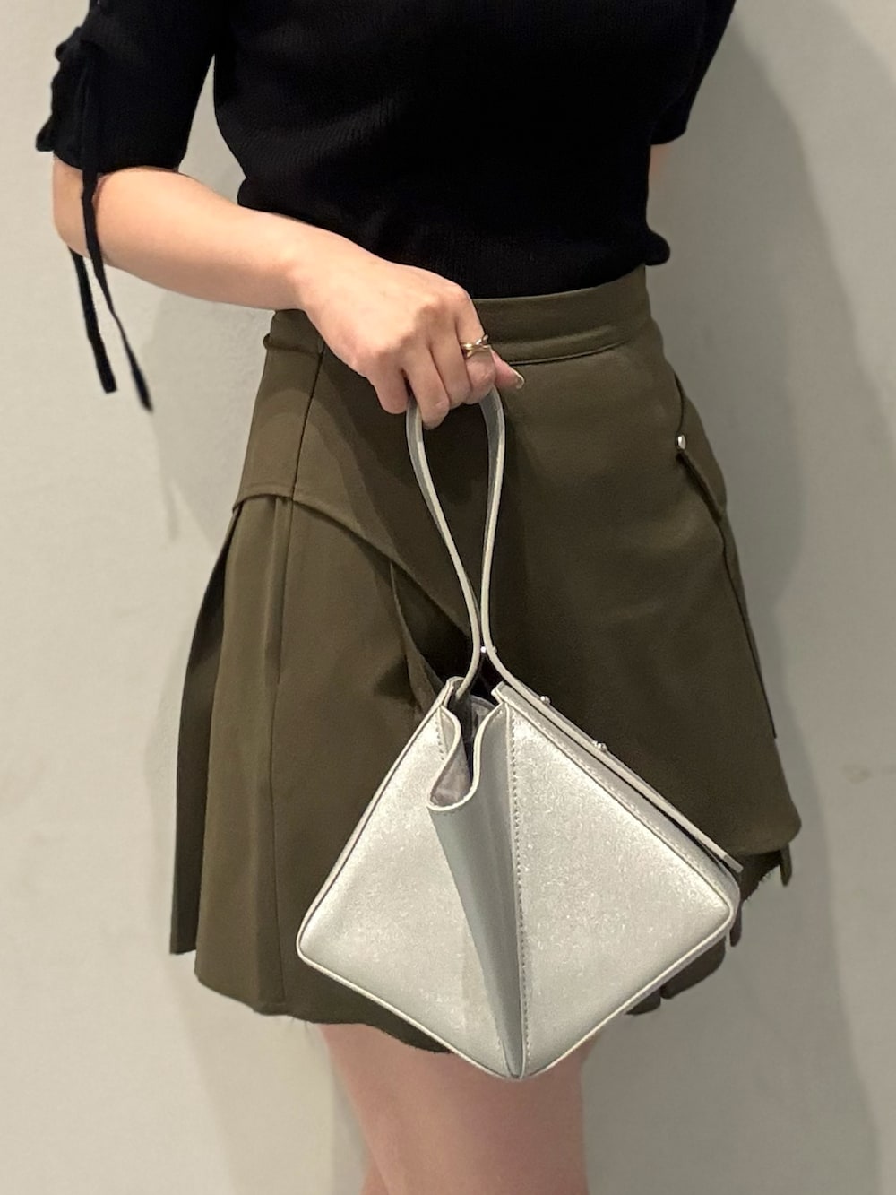 シルバー系のハンドバッグ、ブラック系のサンダル、ブラック系のニット/セーターを着用したレディースの夏コーディネートの6枚目の写真