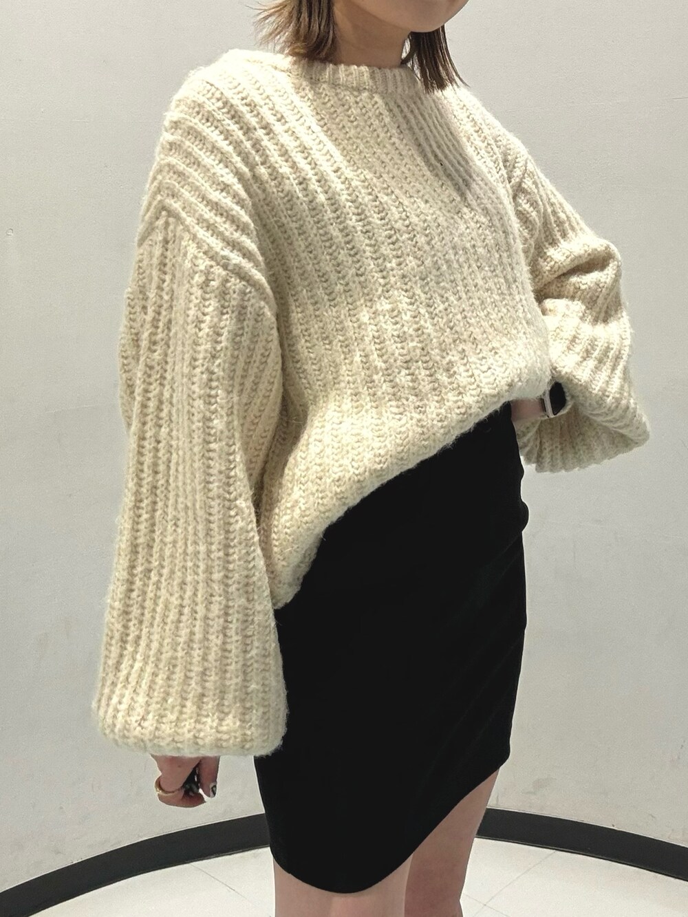 ブラック系のスカート、ホワイト系のニット/セーター、グリーン系のブーツを着用したレディースの秋コーディネートの2枚目の写真