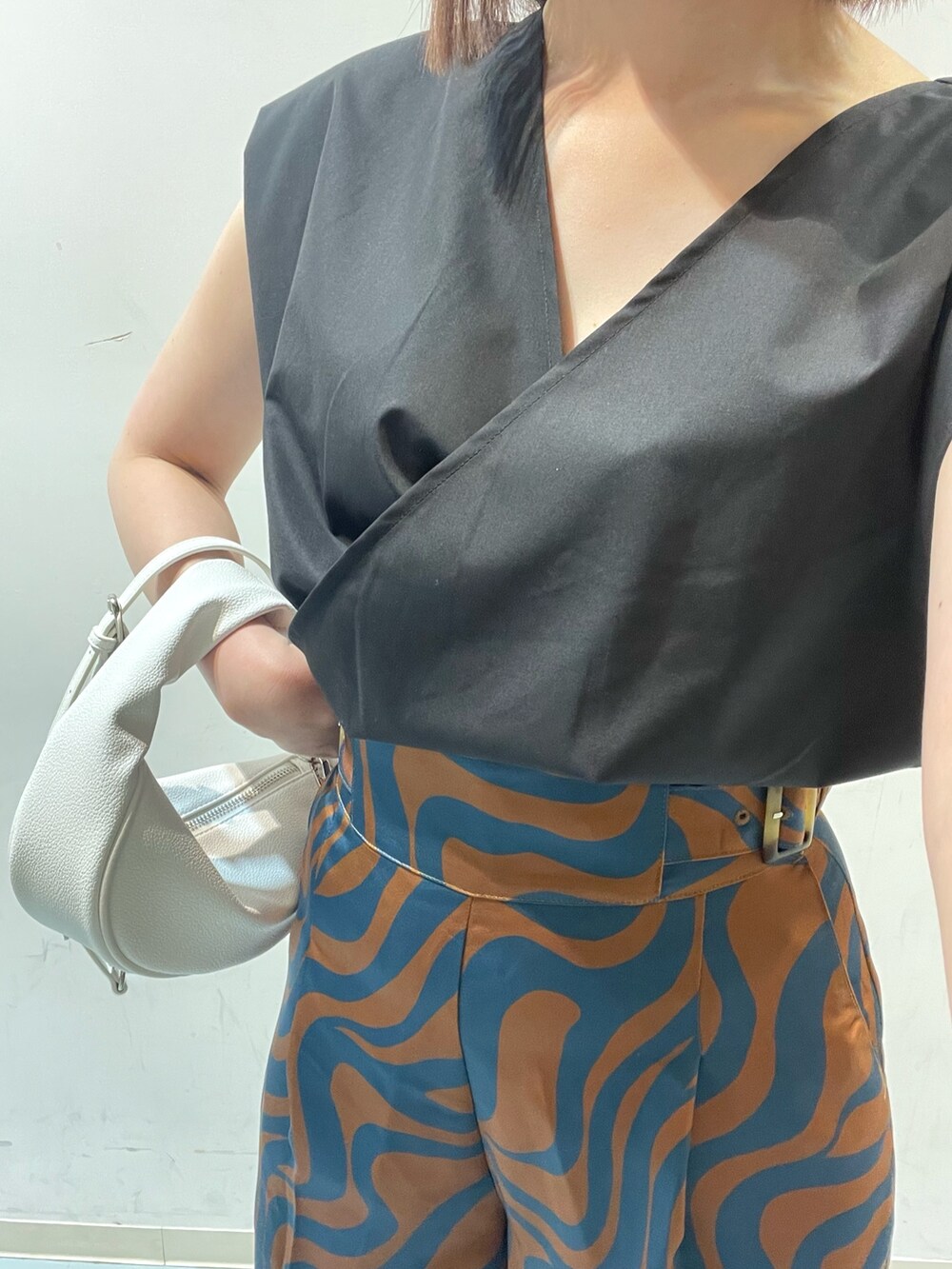 ブラック系のシャツ/ブラウス、ブルー系のスラックス、ホワイト系のハンドバッグを着用したレディースの夏コーディネートの4枚目の写真