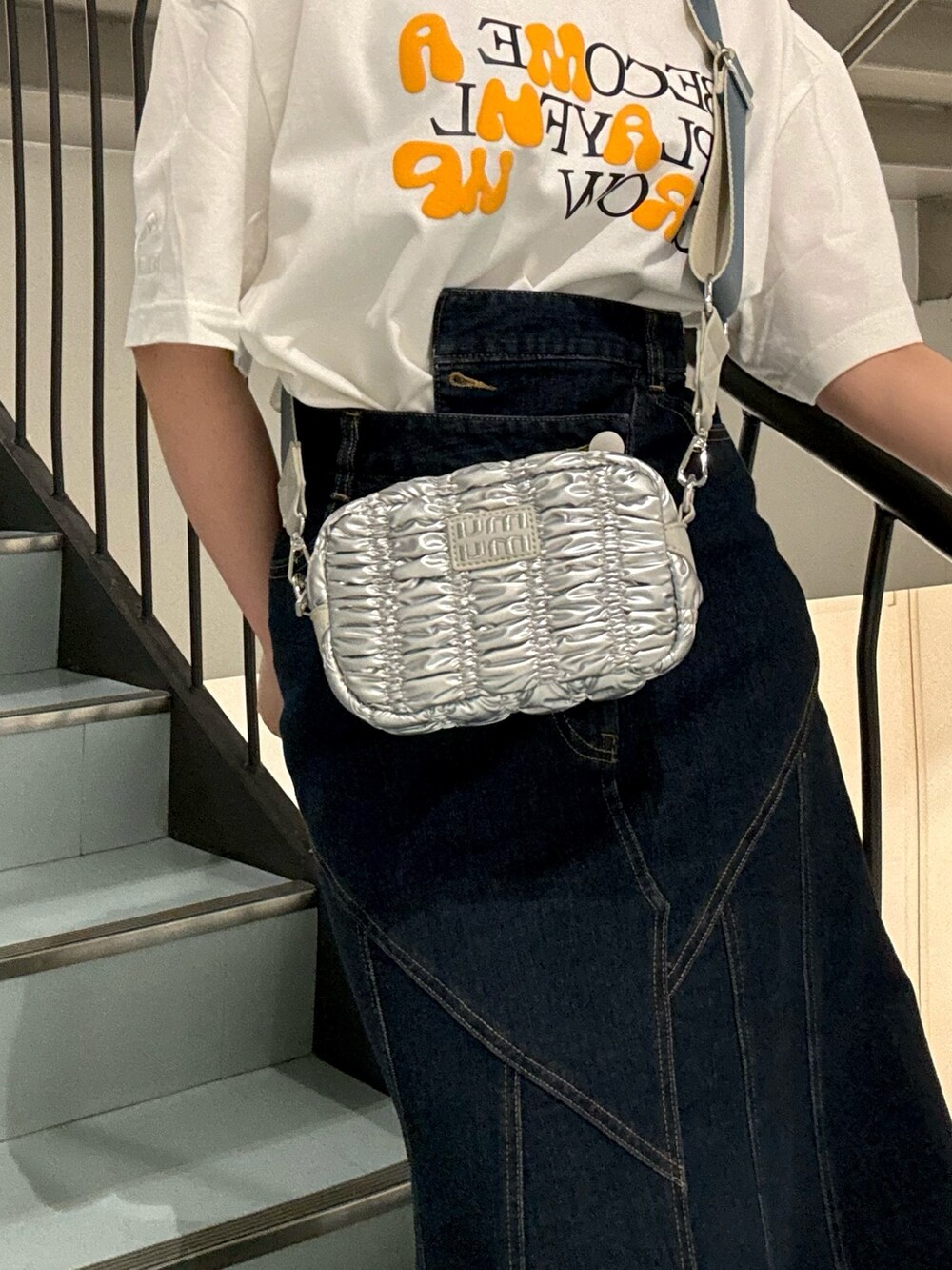 ブルー系のデニムスカート、ホワイト系のTシャツ/カットソー、シルバー系のサンダルを着用したレディースの春コーディネートの5枚目の写真