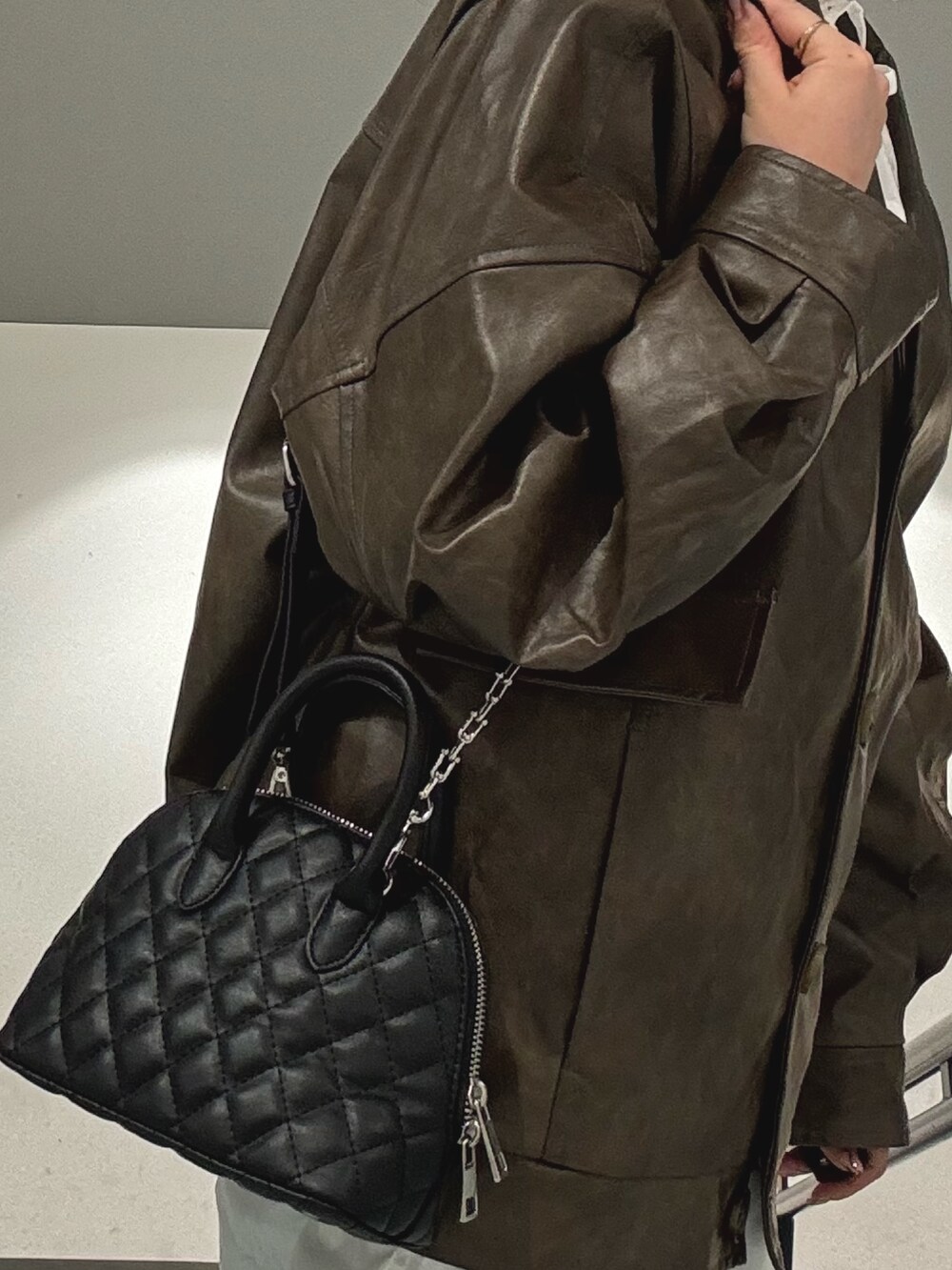 ブラウン系のブルゾン、グレー系のその他パンツ、ブラック系のハンドバッグを着用したレディースの冬コーディネートの6枚目の写真