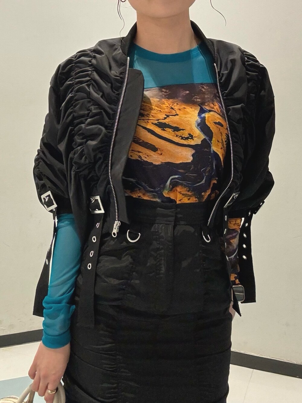 ブラック系のスカート、ホワイト系のハンドバッグ、ブラック系のブルゾンを着用したレディースの春コーディネートの5枚目の写真