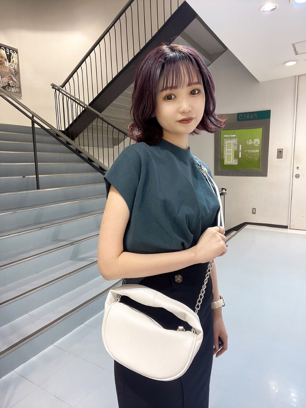 ホワイト系のハンドバッグ、ブラック系のサンダル、グリーン系のTシャツ/カットソーを着用したレディースの春コーディネートの2枚目の写真