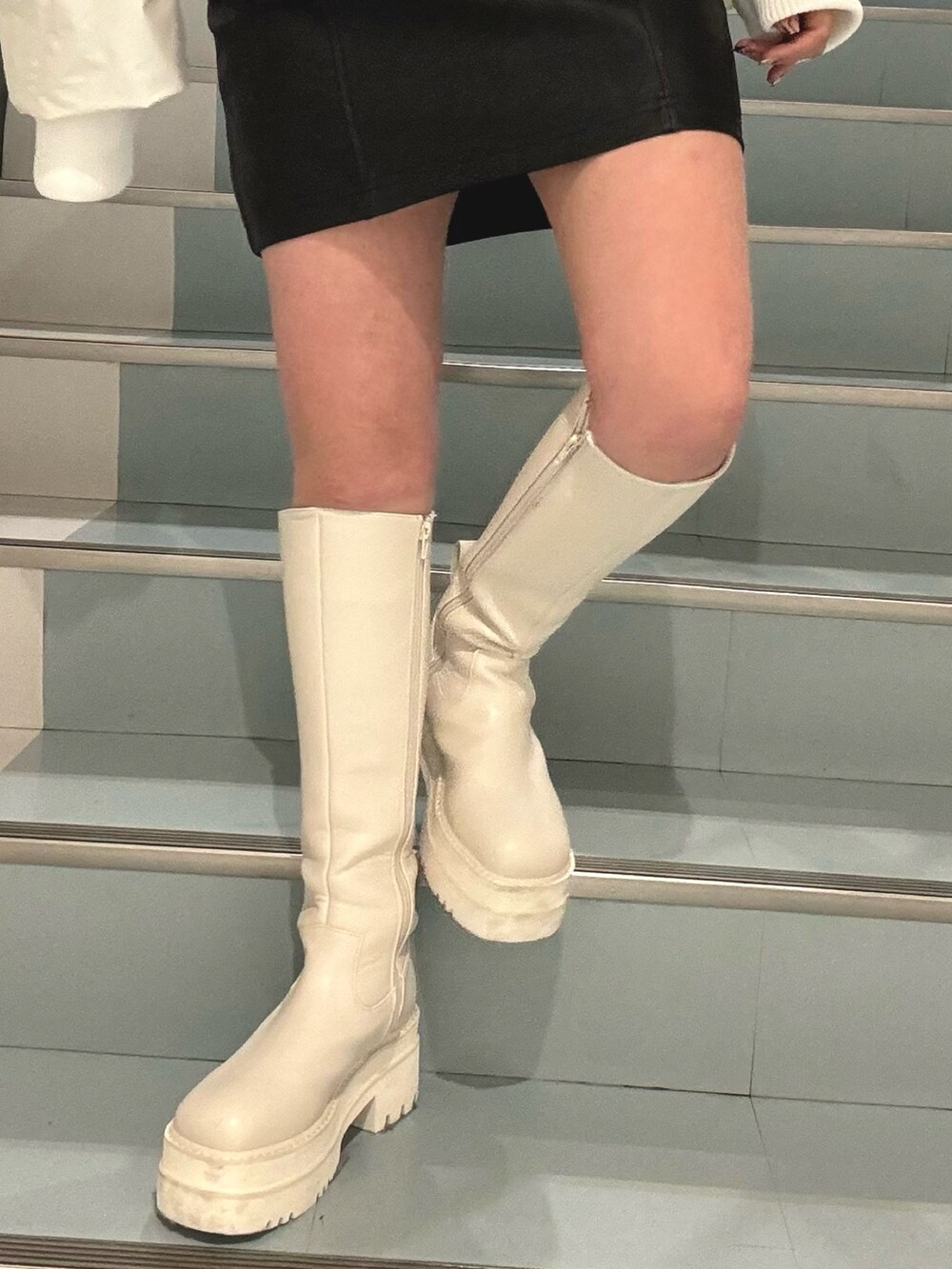 ブルー系のニット/セーター、ホワイト系のブルゾン、ブラック系のスカートを着用したレディースの冬コーディネートの7枚目の写真