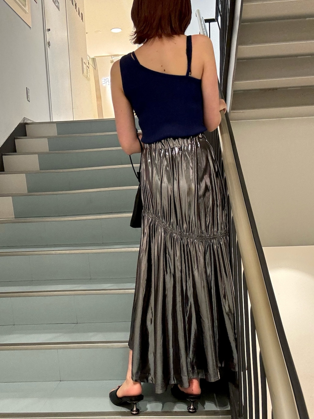 ブラック系のショルダーバッグ、ブラック系のサンダル、ブルー系のニット/セーターを着用したレディースの夏コーディネートの6枚目の写真