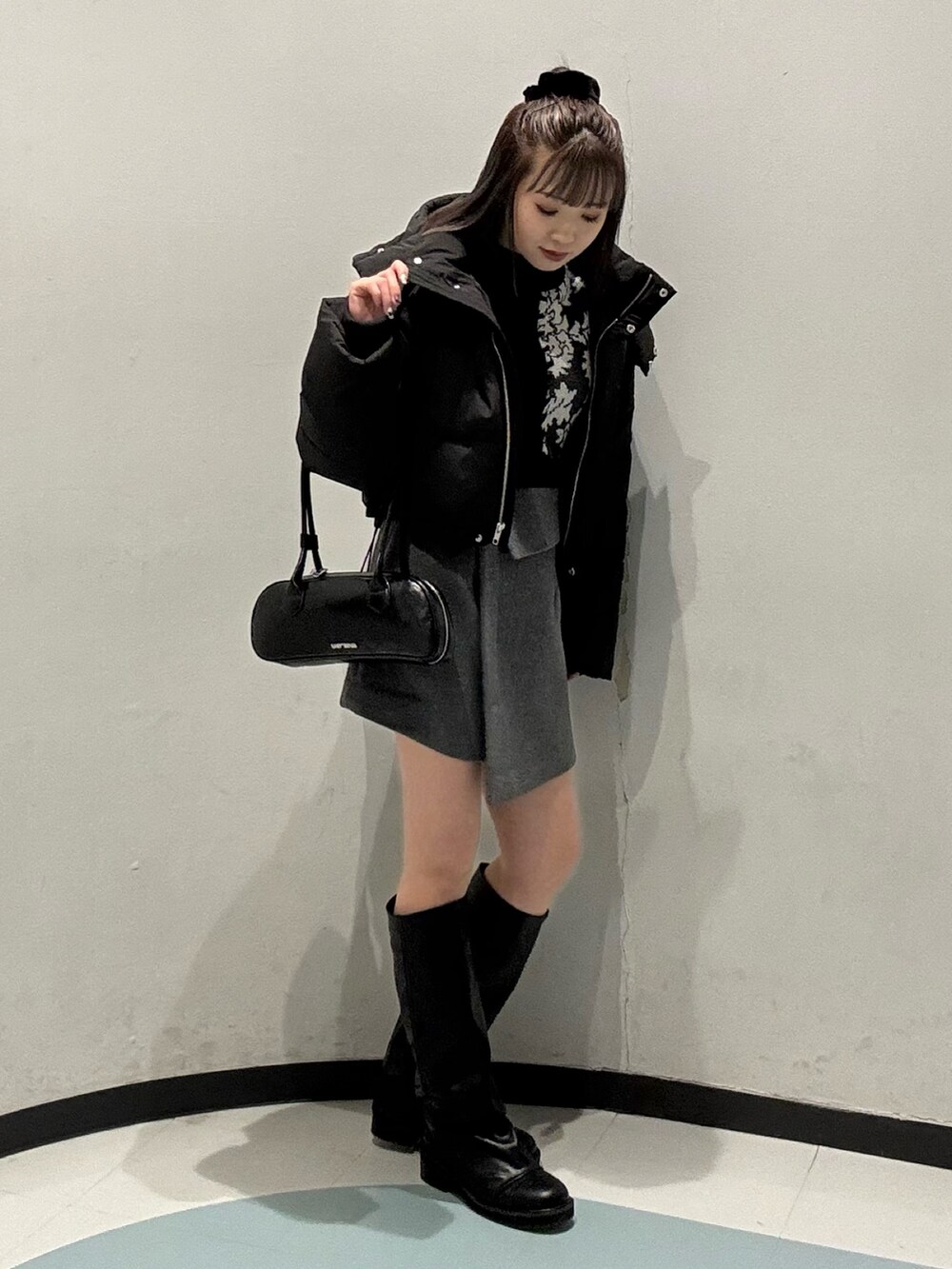 グレー系のスカート、ブラック系のブルゾン、ブラック系のニット/セーターを着用したレディースの冬コーディネートの2枚目の写真