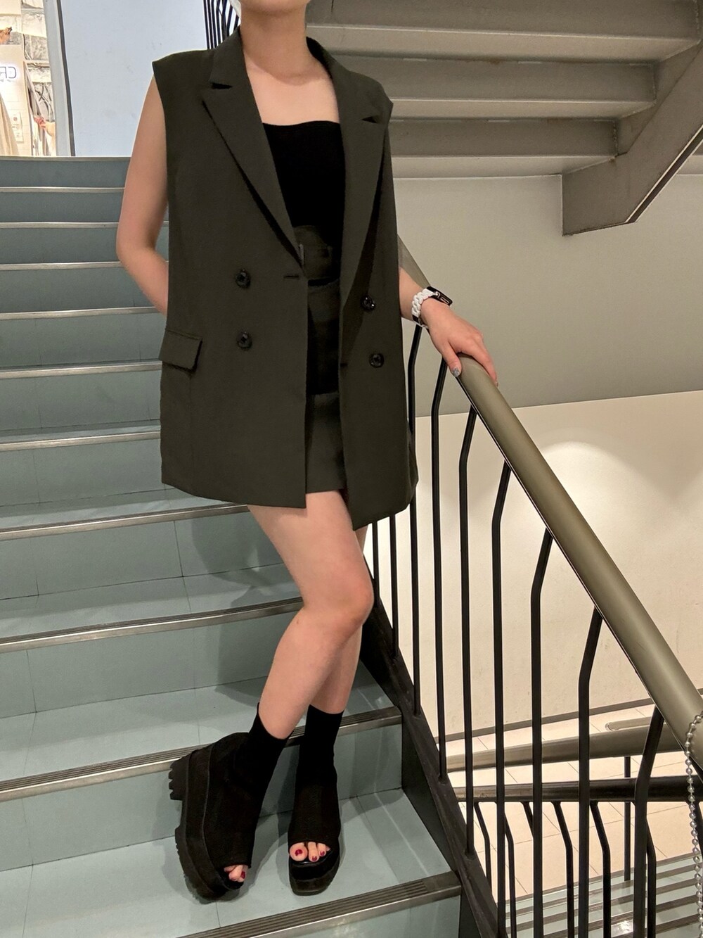 グレー系のベスト、グレー系のスカート、グレー系のショルダーバッグを着用したレディースの春コーディネートの7枚目の写真