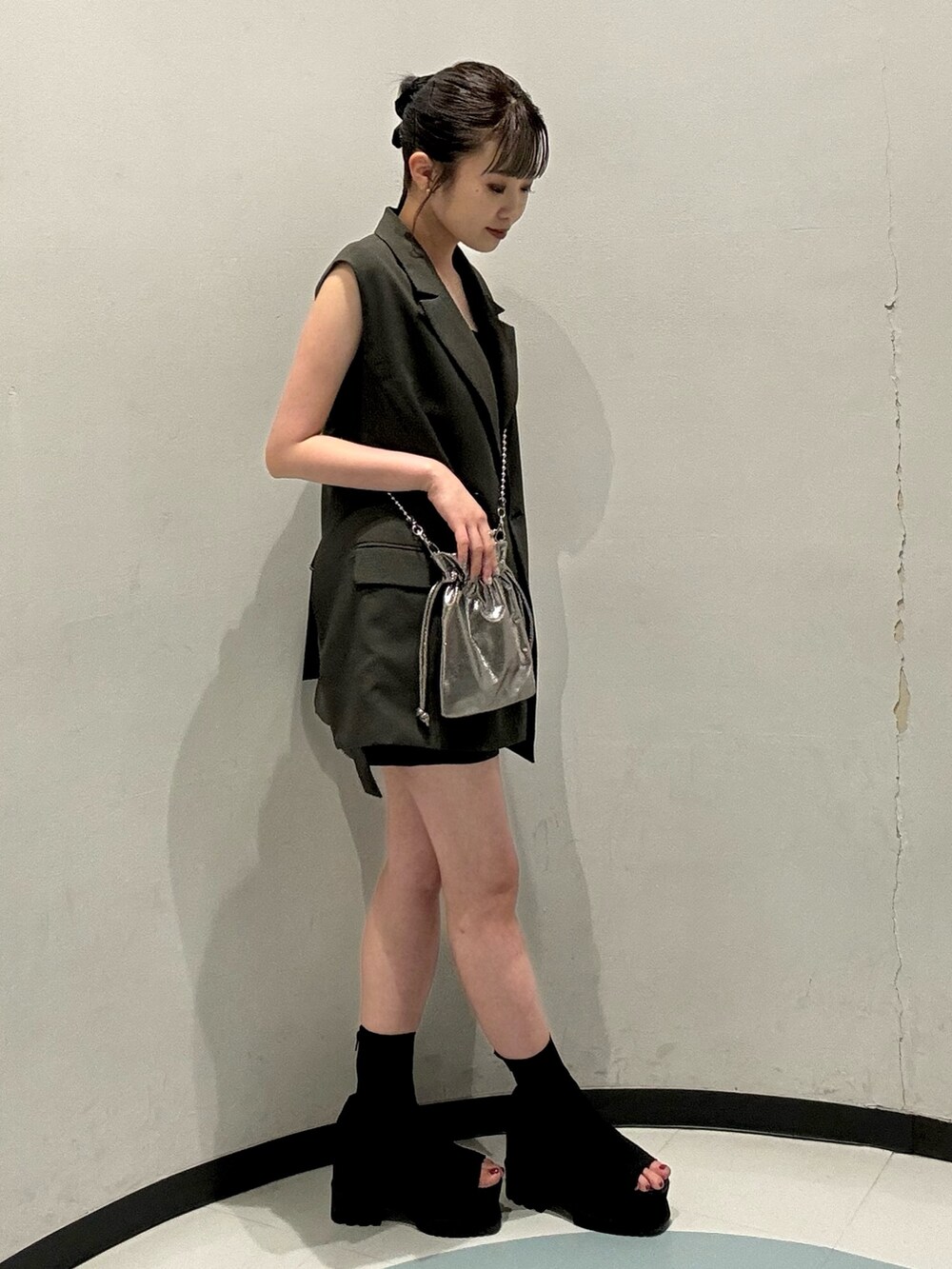 グレー系のベスト、グレー系のスカート、グレー系のショルダーバッグを着用したレディースの春コーディネートの2枚目の写真