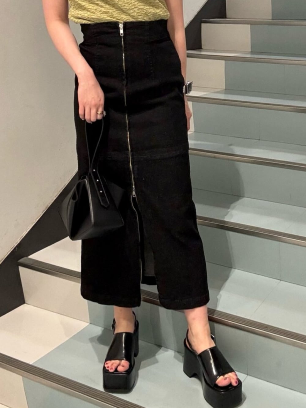 ブラック系のサンダル、グリーン系のタンクトップ、ブラック系のハンドバッグを着用したレディースの夏コーディネートの6枚目の写真