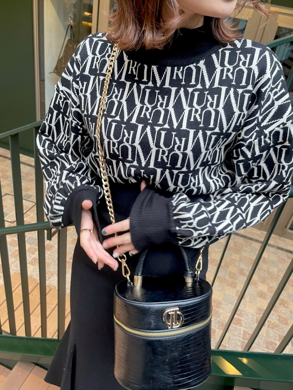 ブラック系のニット/セーター、ブラック系のスカート、グリーン系のムートンコートを着用したレディースの秋コーディネートの4枚目の写真