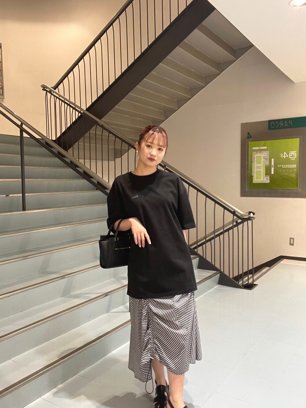 ブラック系のショルダーバッグ、ブラック系のTシャツ/カットソー、ブラック系のサンダルを着用したレディースの春コーディネートの2枚目の写真