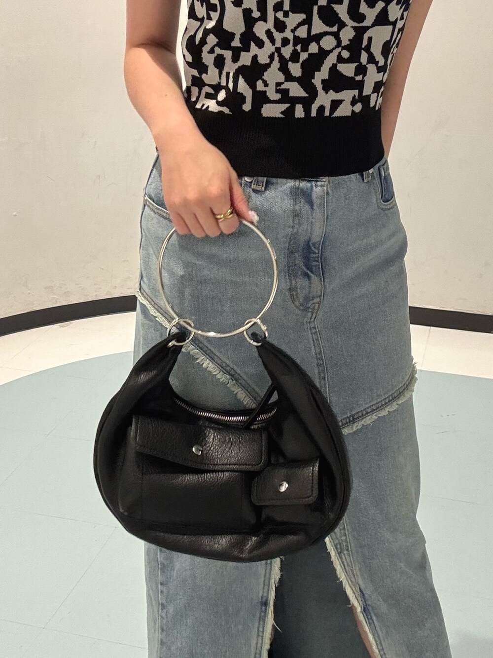 ブラック系のニット/セーター、ブルー系のデニムスカート、ブラック系のサンダルを着用したレディースの夏コーディネートの4枚目の写真