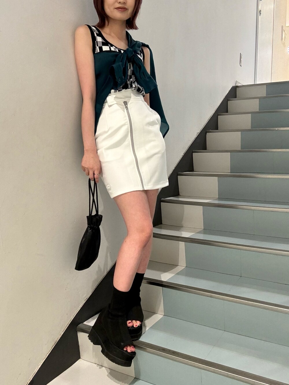 ブラック系のブーツ、ホワイト系のスカート、グリーン系のシャツ/ブラウスを着用したレディースの春コーディネートの4枚目の写真