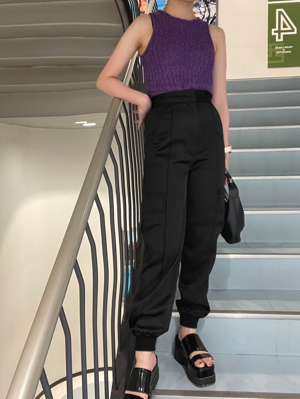 パープル系のタンクトップ、ブラック系のサンダル、ブラック系のスウェットパンツを着用したレディースの夏コーディネートの5枚目の写真