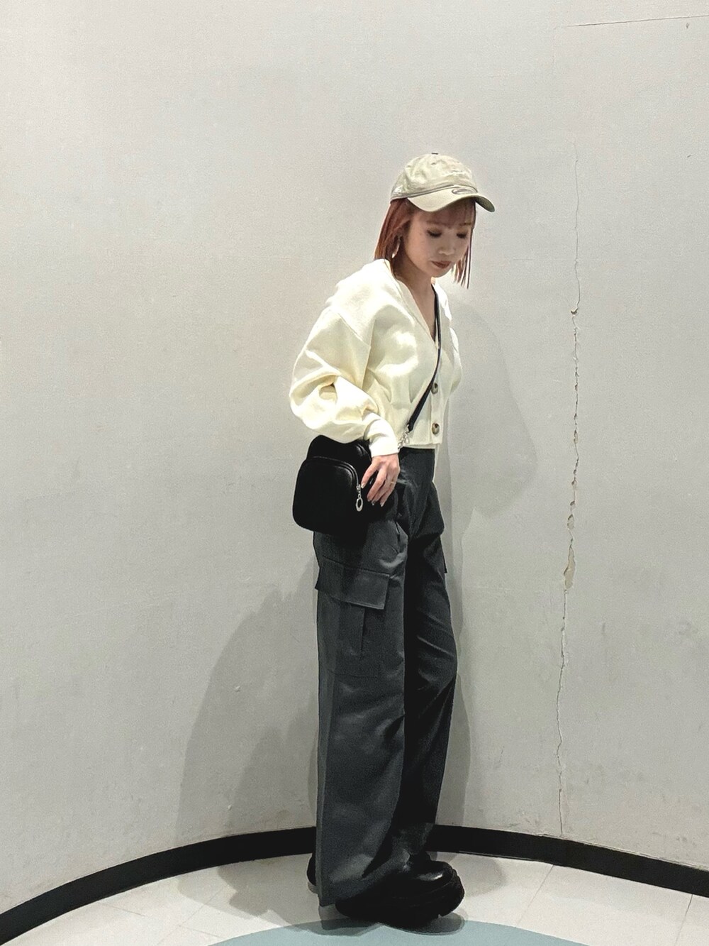 ブラック系のショルダーバッグ、グレー系のカーゴパンツ、ホワイト系のカーディガン/ボレロを着用したレディースの冬コーディネートの2枚目の写真