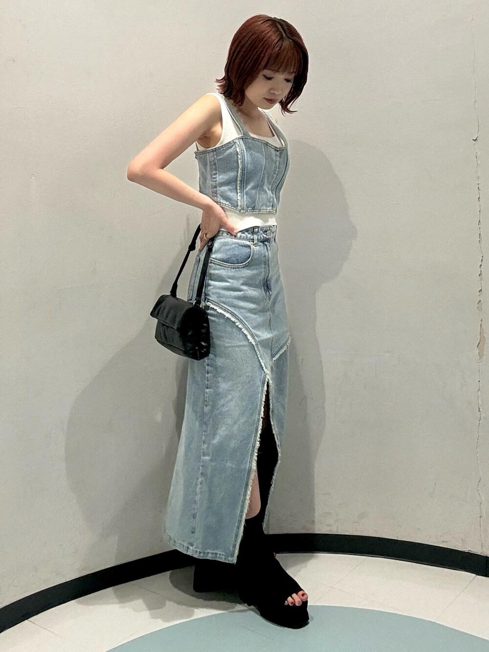 ブラック系のハンドバッグ、ブラック系のブーツ、ブルー系のシャツ/ブラウスを着用したレディースの夏コーディネートの2枚目の写真