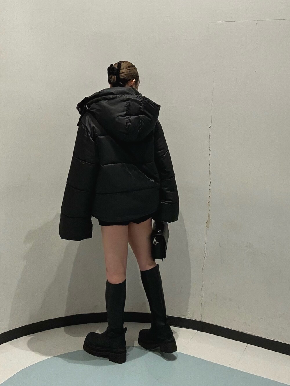 ブラック系のハンドバッグ、ブラック系のブルゾン、ブルー系のニット/セーターを着用したレディースの冬コーディネートの2枚目の写真