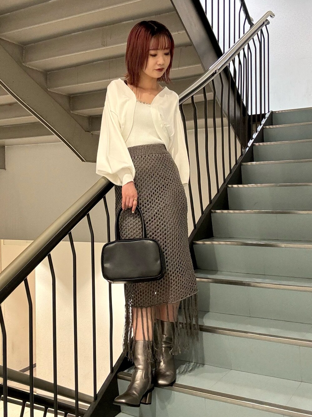 ホワイト系のカーディガン/ボレロ、グレー系のスカート、ブラウン系のブーツを着用したレディースの秋コーディネートの5枚目の写真