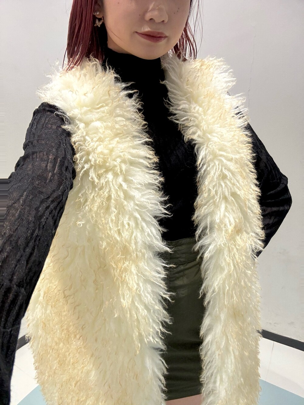 ブラック系のニット/セーター、ホワイト系のベスト、グリーン系のスカートを着用したレディースの秋コーディネートの4枚目の写真