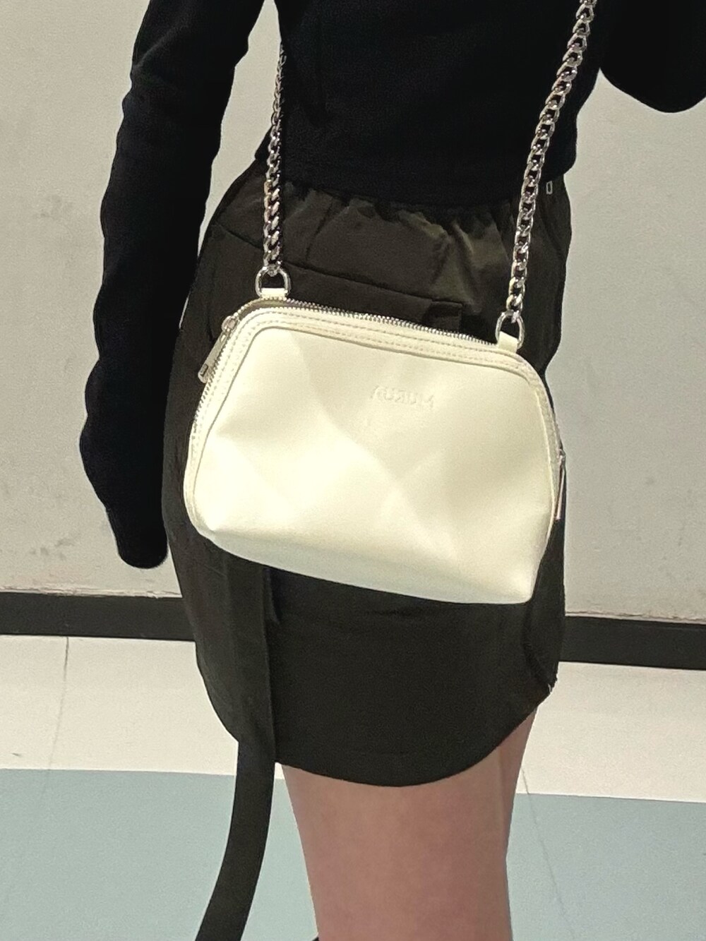 ブラック系のブーツ、ブラック系のTシャツ/カットソー、ベージュ系のスカートを着用したレディースの冬コーディネートの7枚目の写真