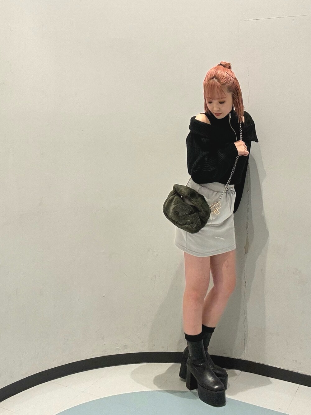 グリーン系のハンドバッグ、グレー系のスカート、ブラック系のニット/セーターを着用したレディースの冬コーディネートの2枚目の写真