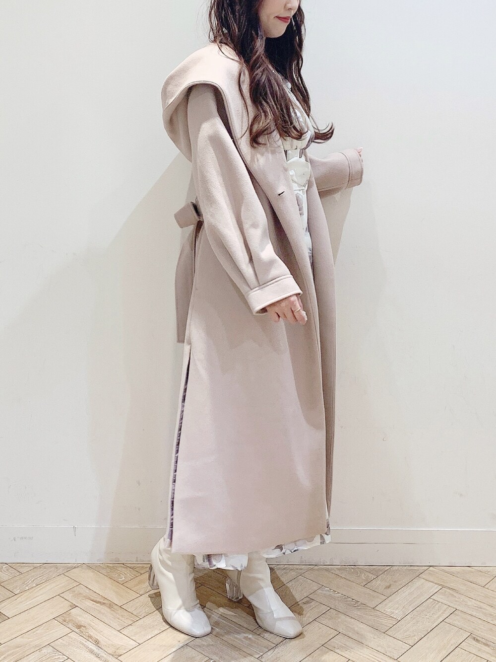 ベージュ系のチェスターコート、ホワイト系のワンピース、ホワイト系のブーツを着用したレディースの冬コーディネートの4枚目の写真