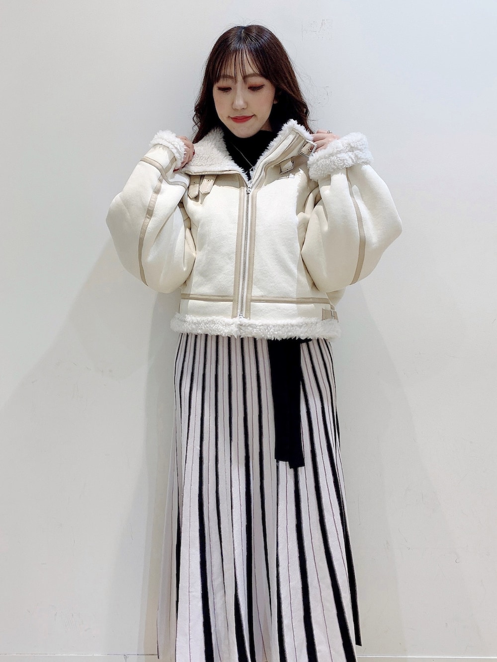 ブラック系のワンピース、ホワイト系のムートンコート、ホワイト系のブーツを着用したレディースの冬コーディネートの9枚目の写真