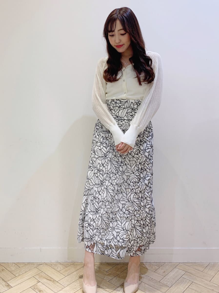 ブラック系のスカート、ホワイト系のニット/セーター、ベージュ系のパンプスを着用したレディースの春コーディネートの2枚目の写真