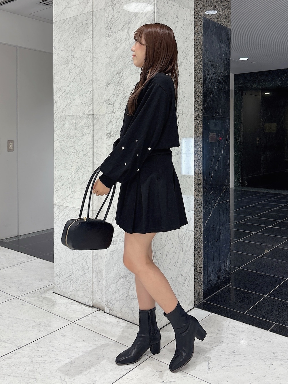 ブラック系のスカート、ブラック系のスウェット、ブラック系のブーツを着用したレディースの秋コーディネートの5枚目の写真