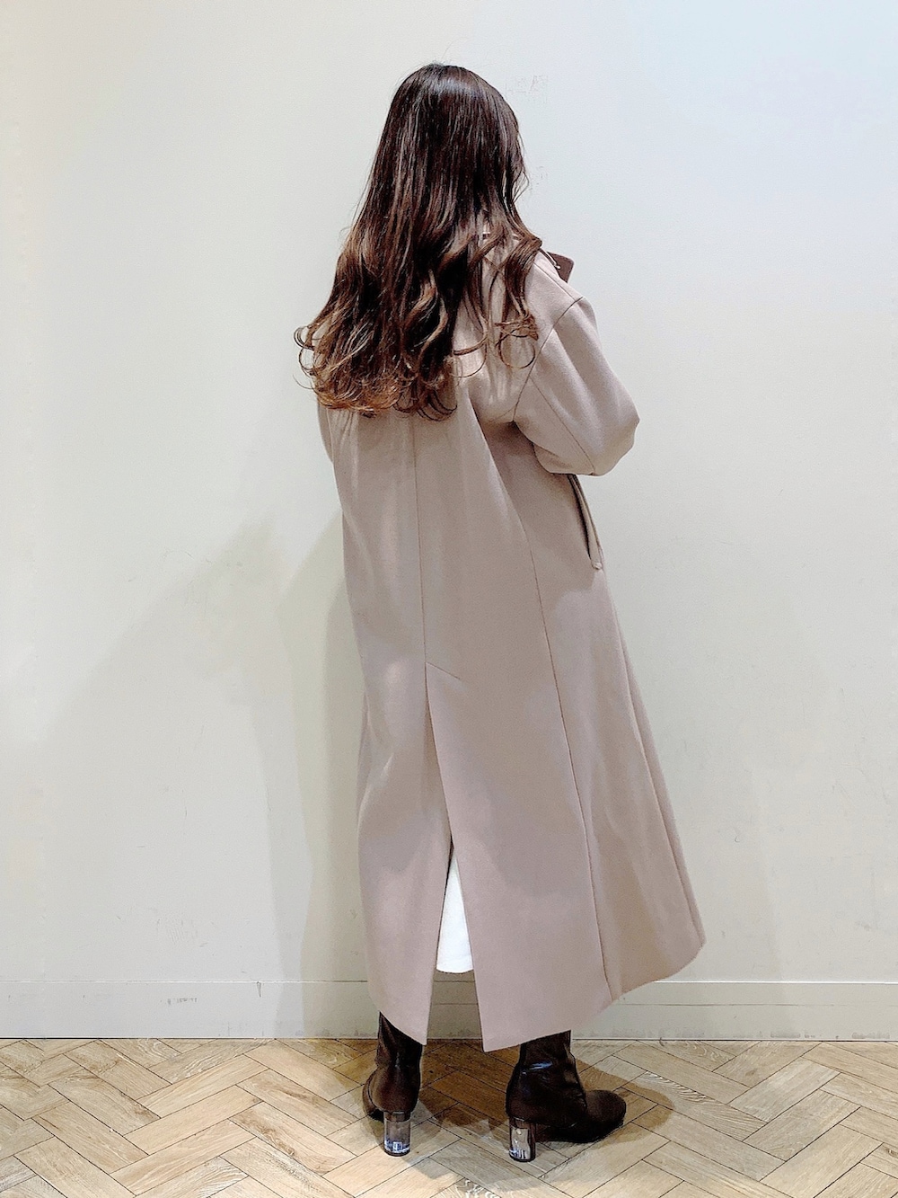 ホワイト系のワンピース、ベージュ系のステンカラーコート、ブラウン系のブーツを着用したレディースの冬コーディネートの9枚目の写真