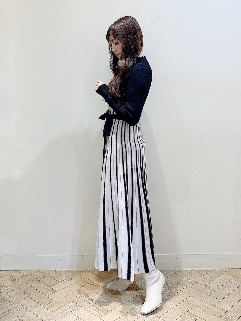 ブラック系のワンピース、ホワイト系のムートンコート、ホワイト系のブーツを着用したレディースの冬コーディネートの2枚目の写真